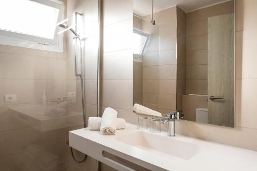 een witte badkamer met een wastafel en een douche bij Apartamentos El Moro in San Antonio