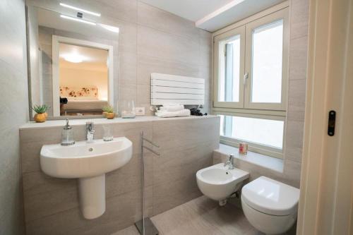 Un baño con lavabo, inodoro y espejo. en Domus Verona - Borsari Pied-à-terre, en Verona