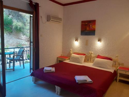 a bedroom with a bed and a balcony with a table at Artemis Rooms in Agia Marina Aegina