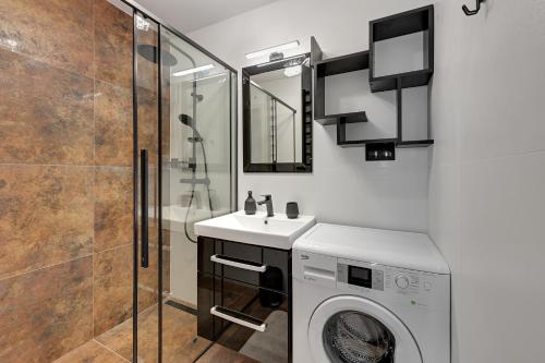 a bathroom with a washing machine and a shower at Platinium Apartament Morski in Gdańsk