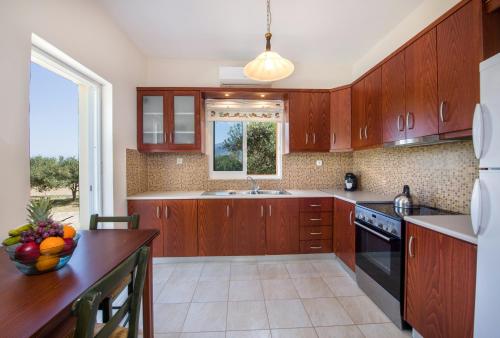 a kitchen with wooden cabinets and a bowl of fruit on a counter at Villa Ciel in Agios Padeleimon