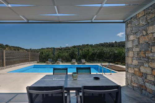 eine Terrasse mit einem Tisch und Stühlen sowie einem Pool in der Unterkunft Kalostous in Agia Triada