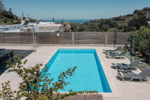 uma piscina com duas espreguiçadeiras e uma casa em Kalostous em Agia Triada