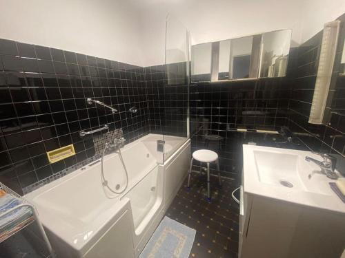 a black tiled bathroom with a tub and a sink at Bastia appartement t4 de charme in Bastia