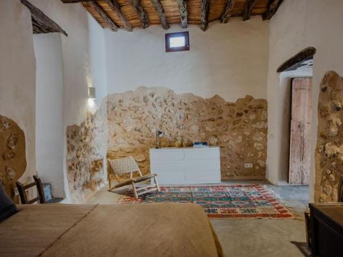1 dormitorio con pared de piedra, cama y escritorio en Cas Orvais con piscina y jardín en Sant Jordi