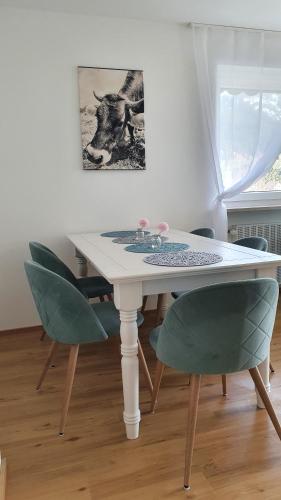una mesa de comedor con sillas verdes y una pintura en Bergjuwel Kleinwalsertal, en Hirschegg