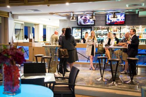 a group of people standing at a bar in a restaurant at Hope Harbour Hotel in Gold Coast