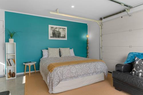 a bedroom with a bed and a blue wall at Marram Studio - Mangawhai Holiday Studio in Mangawhai