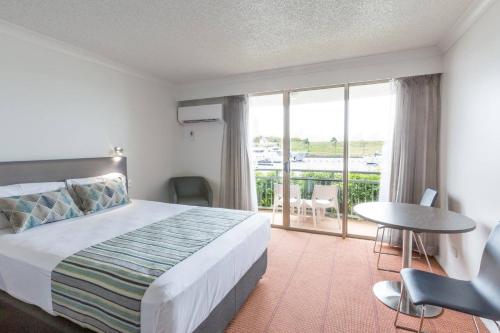 a bedroom with a bed and a table and a balcony at Hope Harbour Hotel in Gold Coast