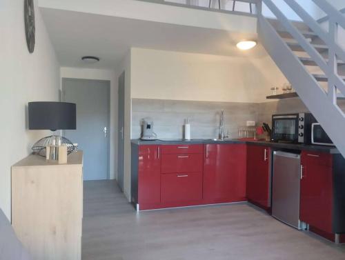 une cuisine avec des placards rouges et un escalier dans l'établissement Calvi duplex climatisé vue mer 4 pers, à Calvi