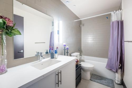 a bathroom with a sink and a toilet and a mirror at GLOBALSTAY New Downtown Hamilton Apartments in Hamilton