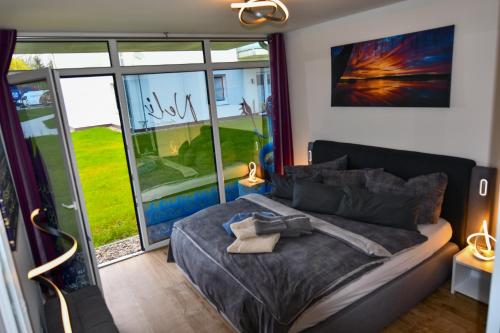 a bedroom with a bed and a large window at Elegantes & modernes Apartment NeLi mit Terrasse, 100m zum Hafen Röbel Müritz in Röbel