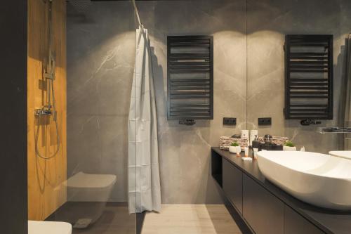 uma casa de banho com um lavatório branco e um chuveiro em Deluxe City Studio Kącik 10 by Renters em Cracóvia