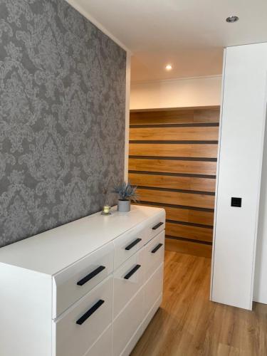 a kitchen with white cabinets and a gray wall at Apartment Ariella in Jūrmala