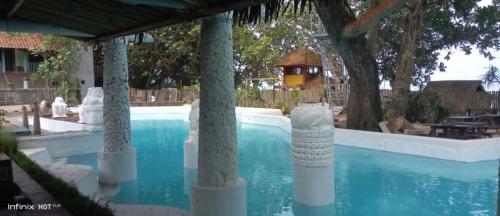 uma piscina com pilares num resort em Noah's Beach Condo at Lippo Carita Utara em Carita