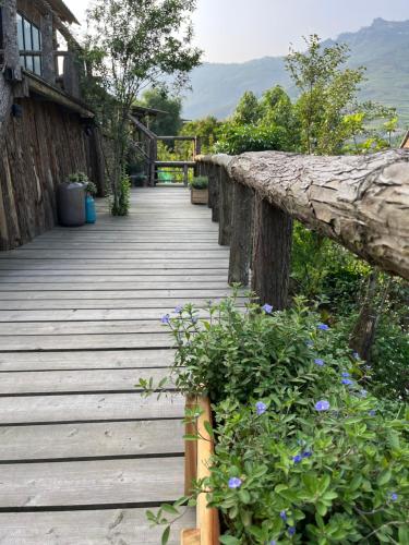 a wooden walkway with purple flowers on the side at H’nee House Ta Van in Sa Pa