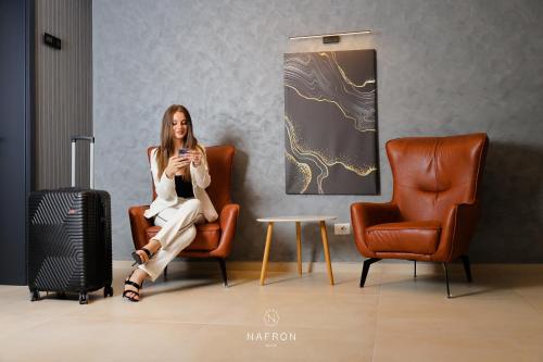 a woman sitting in a chair next to a suitcase at Nafron Hotel in Prizren