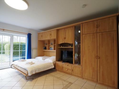 a bedroom with a bed and wooden cabinets and a television at Mensendiek, Anita, App in Zingst
