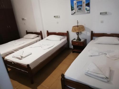 two twin beds in a room with a lamp at Christina Pension in Karterados