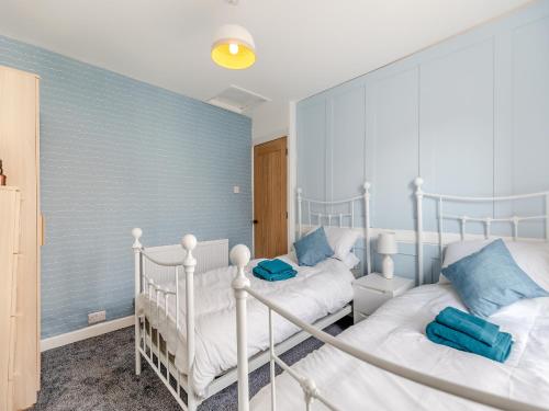 2 camas individuales en un dormitorio con paredes azules en Primrose Cottage, en Teignmouth