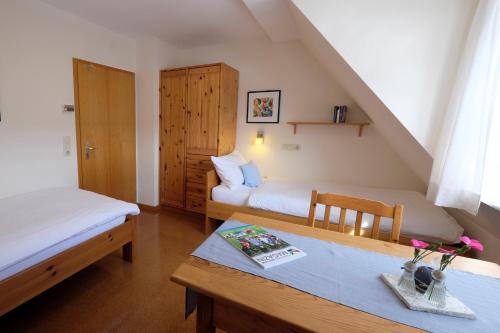 una habitación con 2 camas y una mesa con flores. en Gästehaus am Brombachsee, en Pfofeld