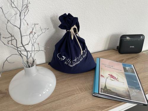 a table with a blue bag and a vase and a book at Pension Villa Frohsinn Sellin auf Rügen in Ostseebad Sellin