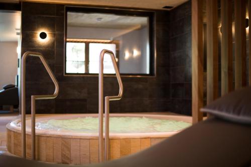 a jacuzzi tub in a room with a mirror at Hostellerie Des Châteaux & Spa in Ottrott