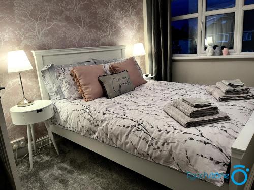 - une chambre avec un lit doté d'oreillers roses et d'une fenêtre dans l'établissement Cosy Home with links to B'ham, Solihull, NEC, M42, à Sheldon