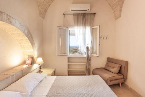 a bedroom with a bed and a chair and a window at VILLA Alessandra in Marina di Pescoluse
