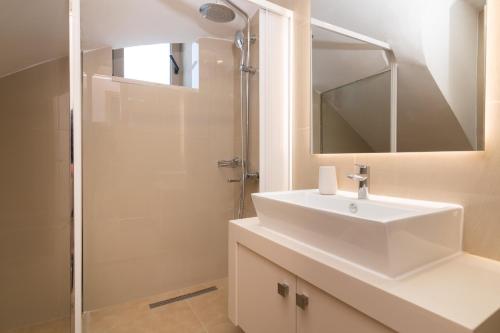 a white bathroom with a sink and a shower at Claudio Stone House in Vasilikos