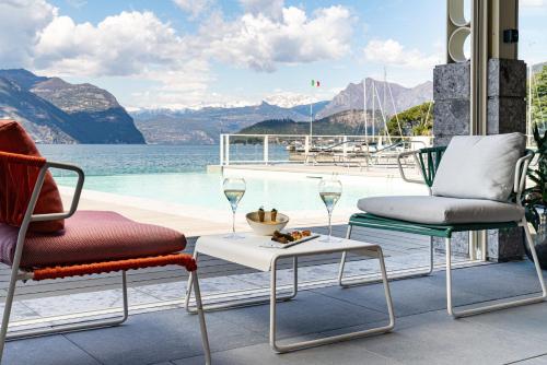 a patio with two chairs and a table with wine glasses at Araba Fenice Hotel in Iseo