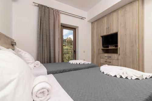 a hotel room with two beds and a television at Claudio Stone House in Vasilikos