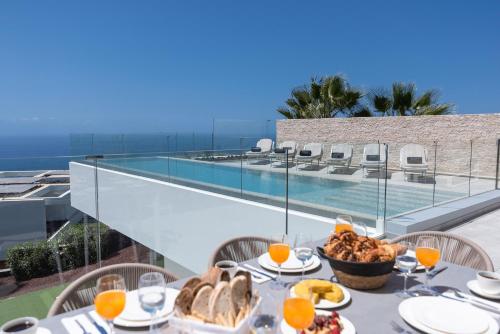una mesa con comida en el balcón con vistas al océano en KARAT Villa Zambrano - INCLUDES GOLF CART and DAILY MAID SERVICE, en Guía de Isora