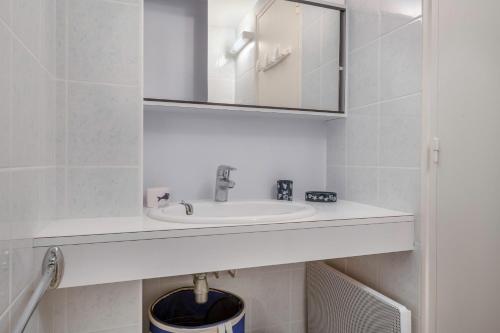 une salle de bain blanche avec un lavabo et un miroir dans l'établissement Appartement à 150m de la plage, à La Baule