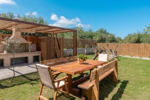 a wooden table and chairs in a garden at Claudio Stone House in Vasilikos