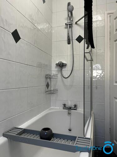 a bathroom with a bath tub with a shower at Cosy Home with links to Bham, Solihull, NEC, M42 in Sheldon