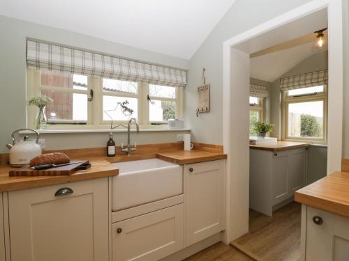 a kitchen with white cabinets and a sink at Pool Cottage in Hereford