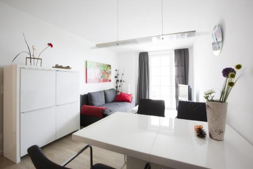 eine weiße Küche und ein Wohnzimmer mit einem weißen Tisch und Stühlen in der Unterkunft Residenz am Balmer See - BS 09 mit Wellnessbereich in Balm