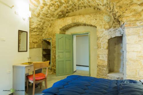 a bedroom in a stone building with a bed and a desk at Al-Hakim Boutique Hotel Old Town Nazareth in Nazareth