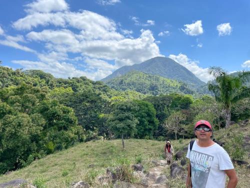 un hombre de pie en una colina con una montaña en el fondo en PALOMINO- HOSTEL BALNEARIO RIO ANCHO, en Palomino