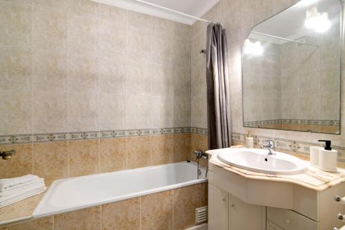 a bathroom with a tub and a sink and a bath tubermottermott at Apartamento Serra e Mar in Alvor