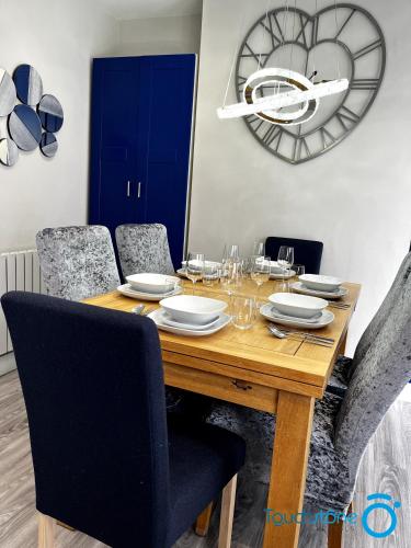 a dining room table with chairs and a clock on the wall at Cosy Home with links to Bham, Solihull, NEC, M42 in Sheldon