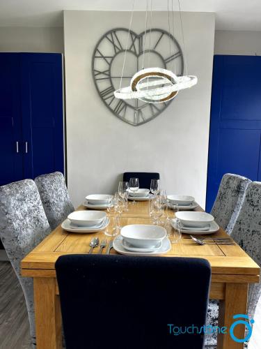 a dining room table with plates and wine glasses at Cosy Home with links to Bham, Solihull, NEC, M42 in Sheldon