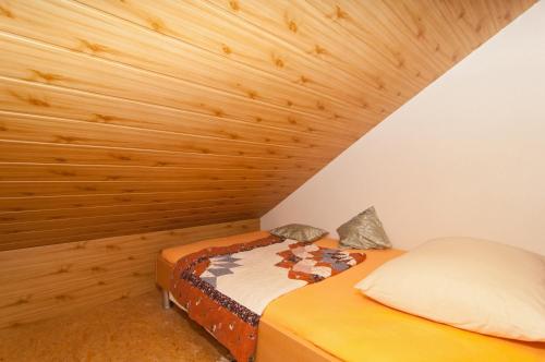 Ce lit se trouve dans un dortoir doté d'un plafond en bois. dans l'établissement Apartments Corana, à Kaštela