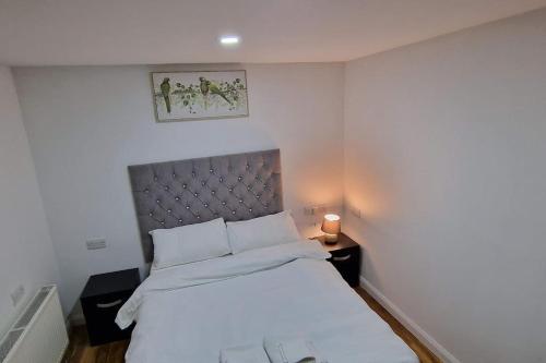 a bedroom with a white bed with a silver headboard at 1 Bedroom Studio in Eltham