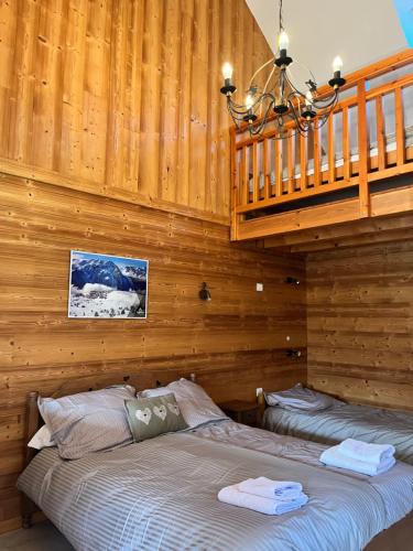 a bedroom with two beds in a wooden wall at Le Catelan in La Paute