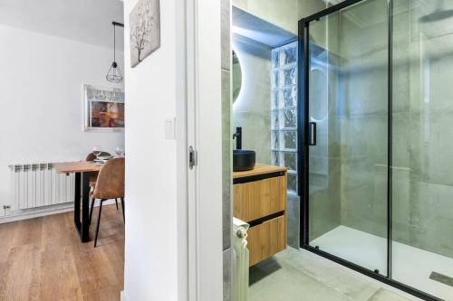 een glazen douche in een badkamer met een tafel bij MyHouseSpain - Acogedor piso nuevo en Gijón in Gijón