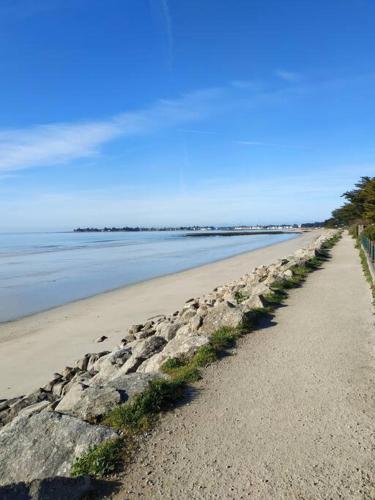 a sandy beach with a rock wall and the ocean at Grand studio, tout équipé et rénové. in Combrit