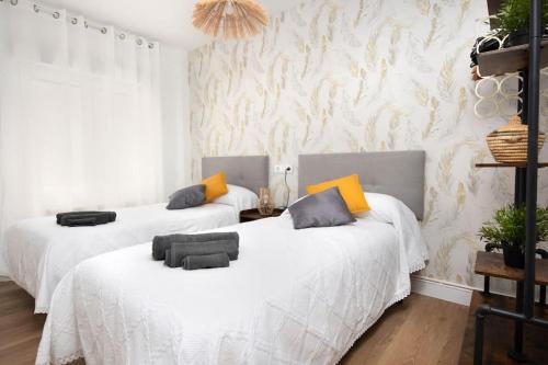 2 bedden in een kamer met witte en oranje kussens bij MyHouseSpain - Acogedor piso nuevo en Gijón in Gijón