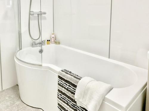 a white bath tub in a bathroom with a towel on it at Leddon Farm Annexe-uk39616 in Gooseham